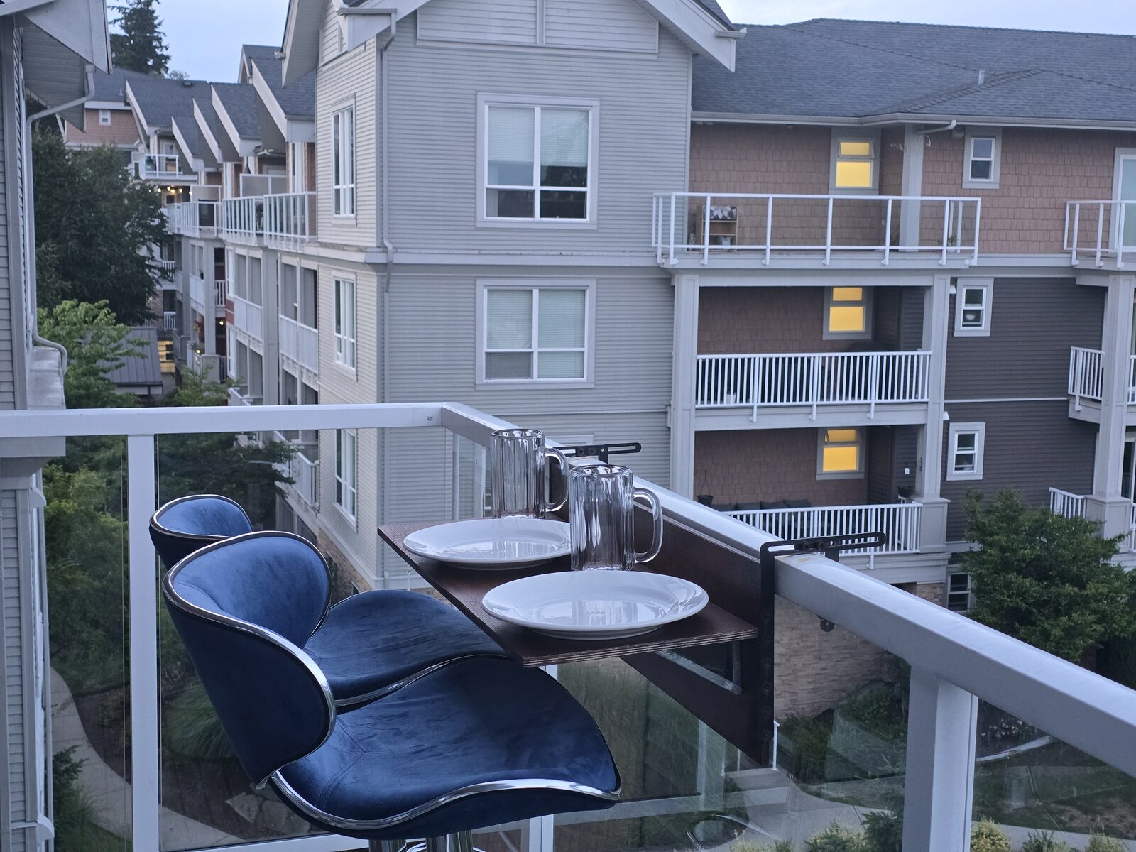 Folding bar table with two chairs on the balcony, set for dinner with a view of the neighborhood