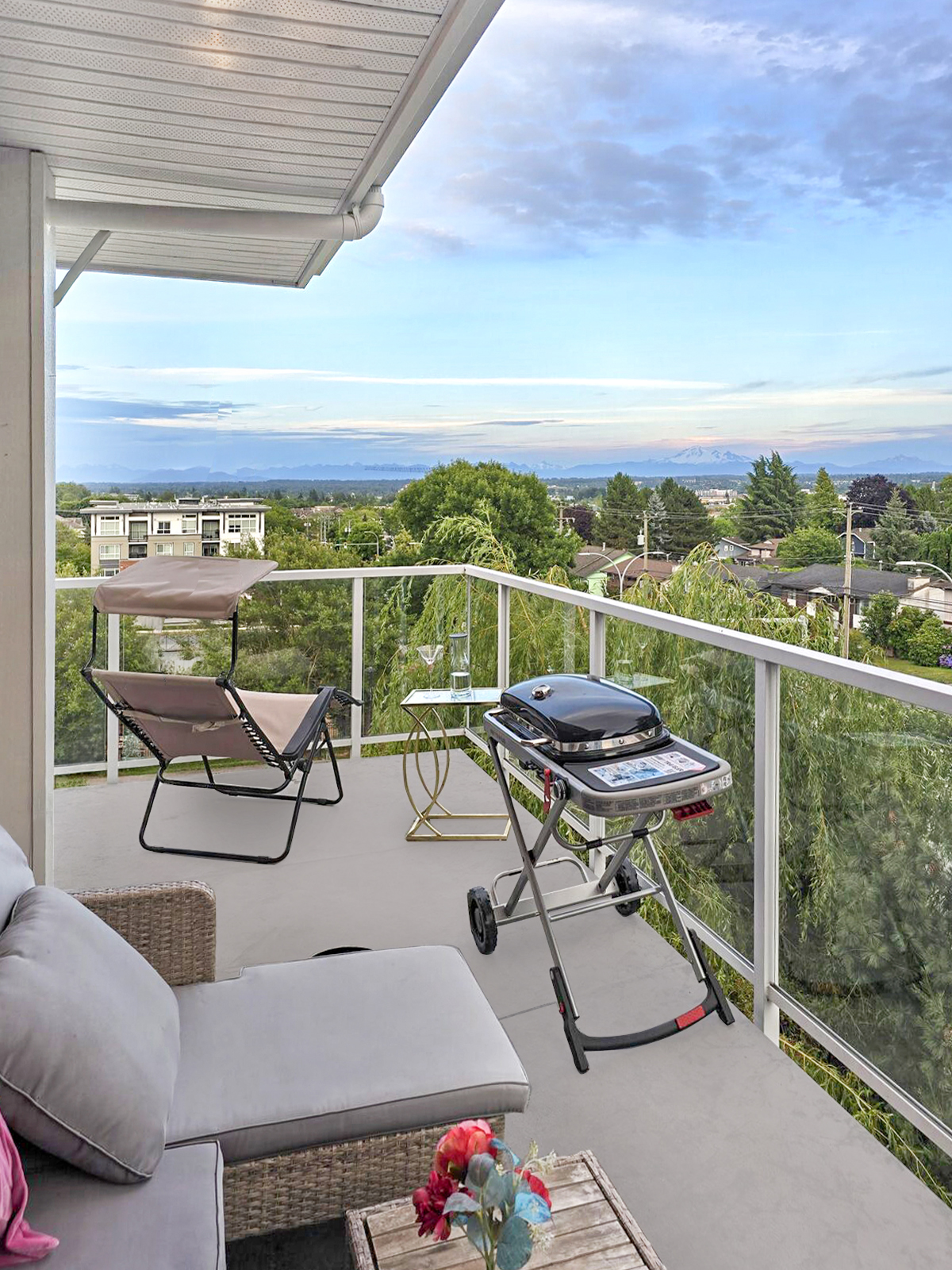 Wraparound balcony view from the living room entrance toward the lounge and BBQ area, with Mount Baker in the distance