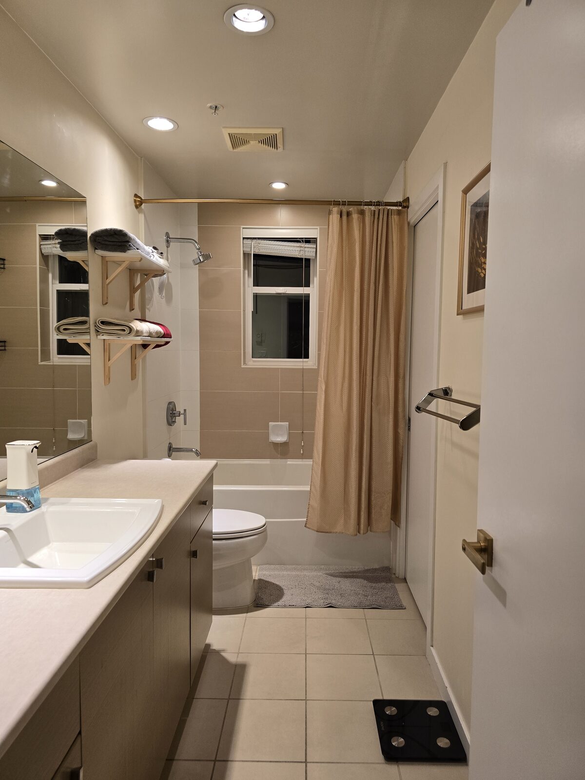 Bright bathroom with vanity, soaker tub, and shower curtain, smart scale on the floor