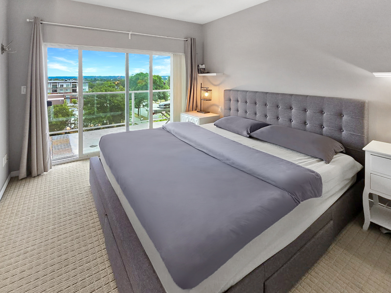 Wide view of the bedroom showing the king bed, balcony access, and bedside lamp glow