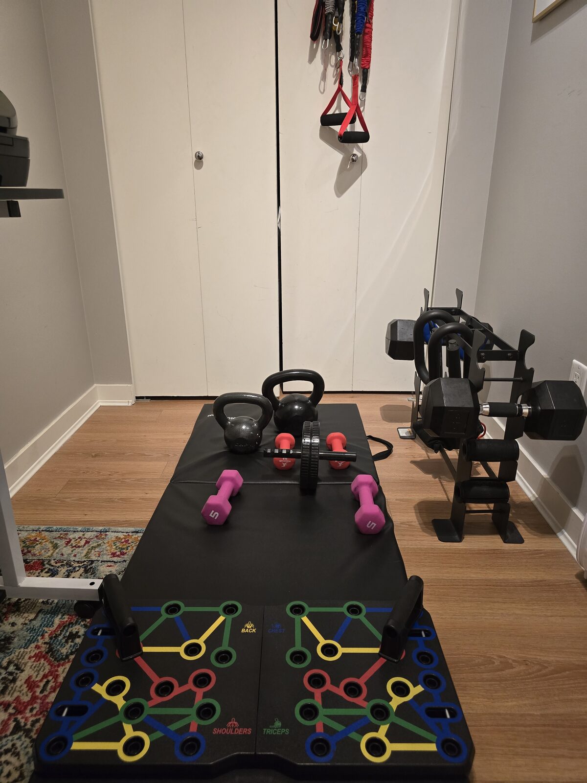 Close-up of dumbbells, kettlebells, ab roller and push-up board laid out on exercise mat