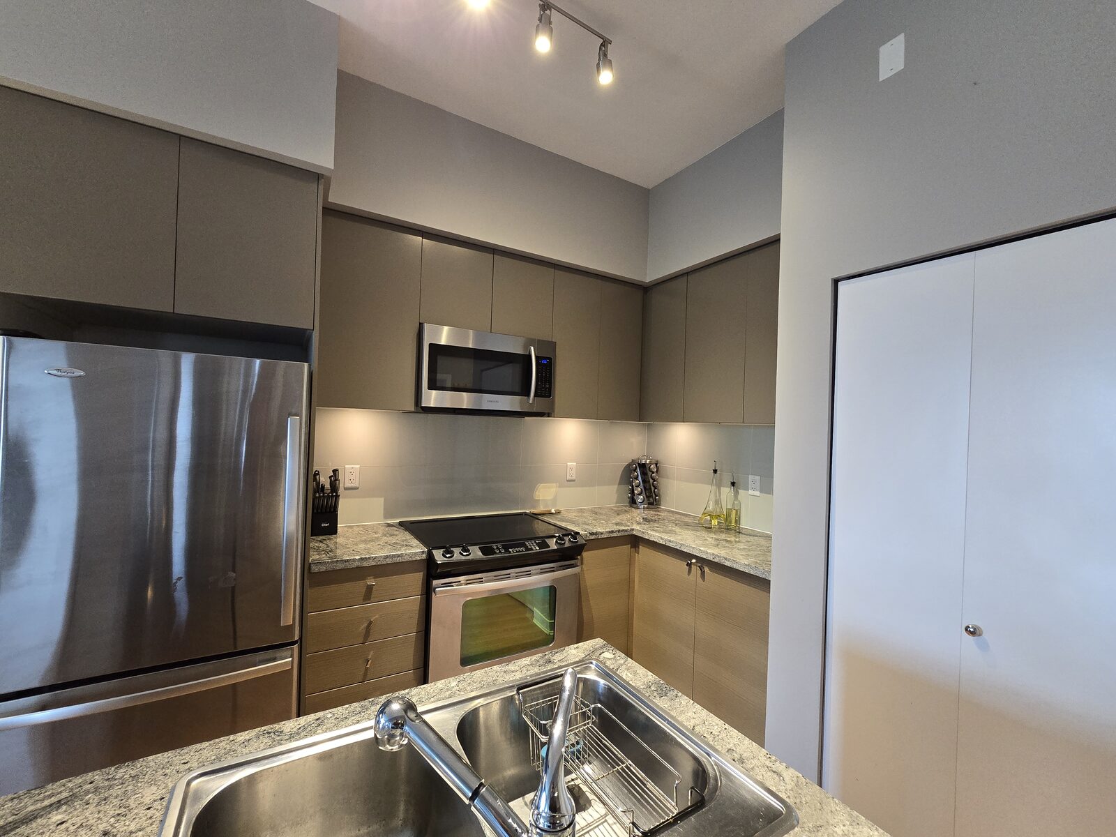 Kitchen sink, stainless refrigerator, and L-shaped granite counter