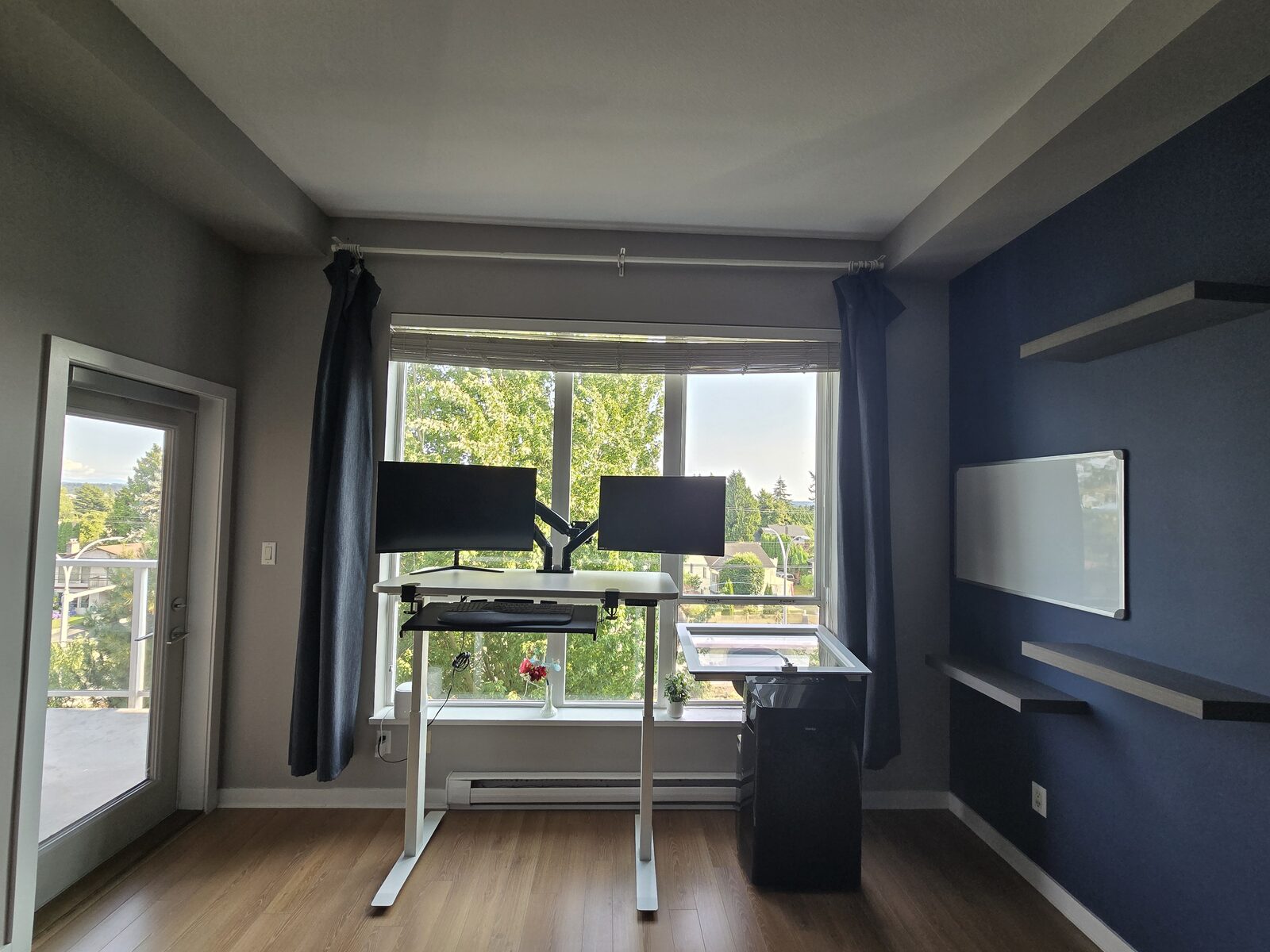 Standing desk with dual monitors set up in front of the window